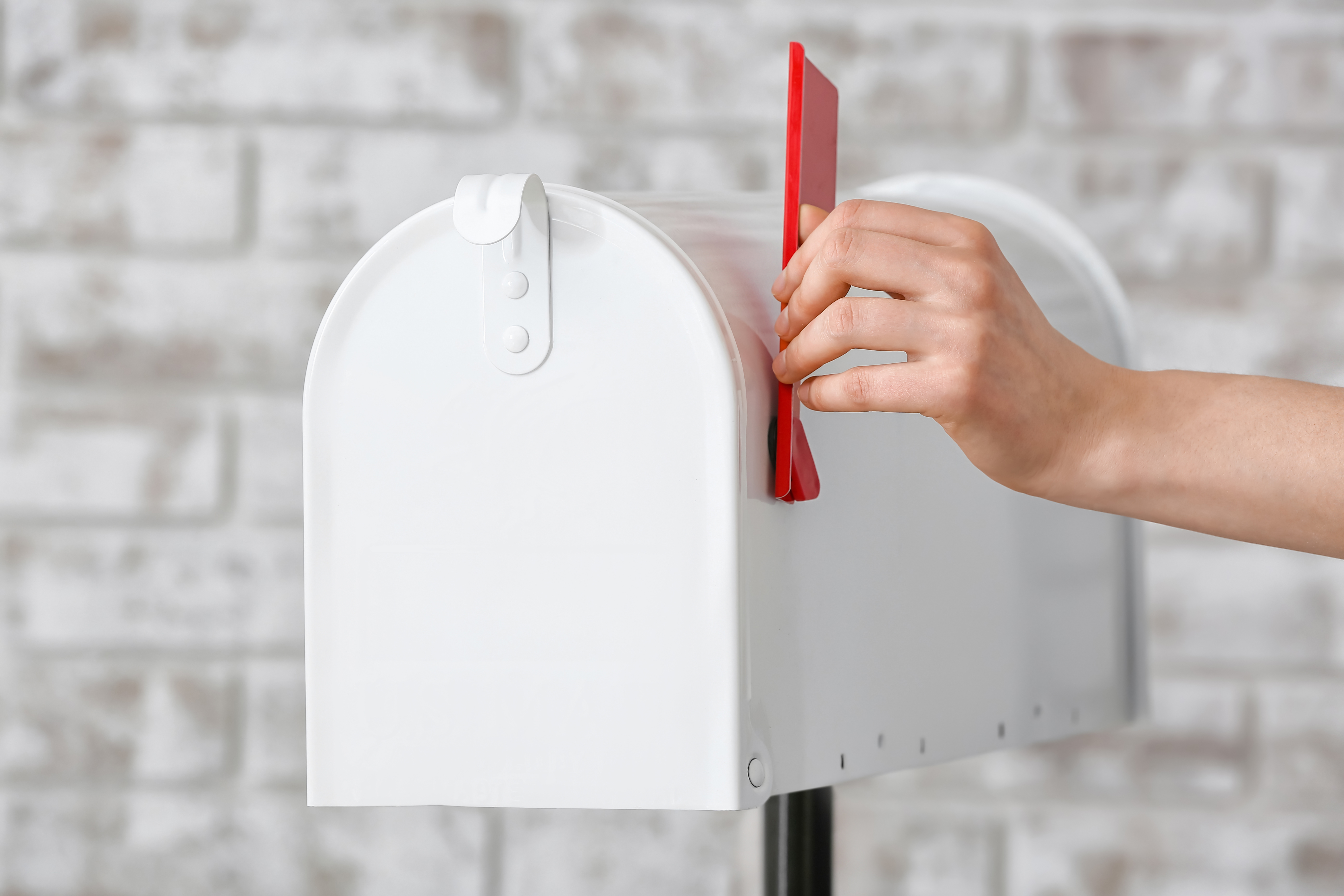 Hand placing mail in white mailbox