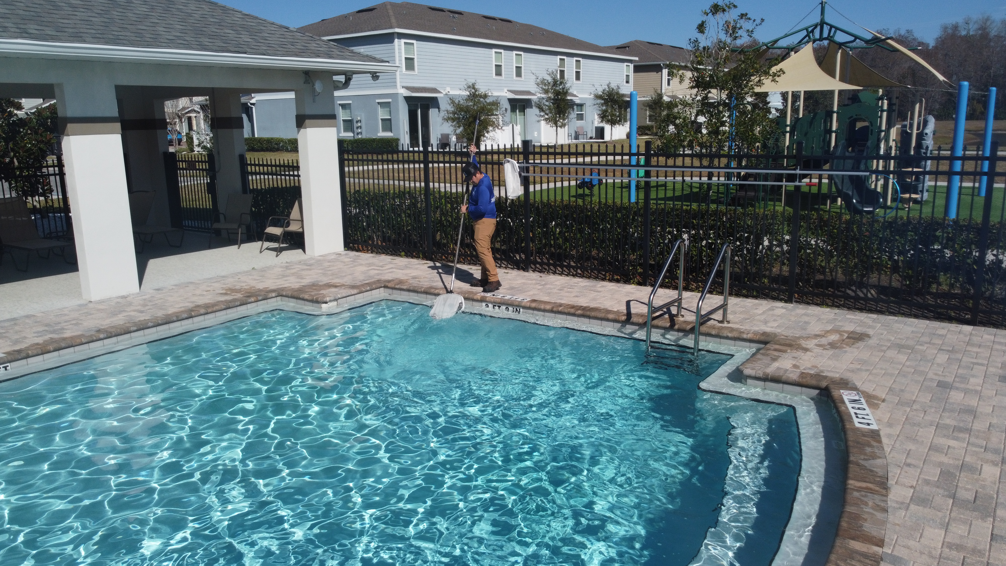 Pool maintenance technician servicing a residential pool