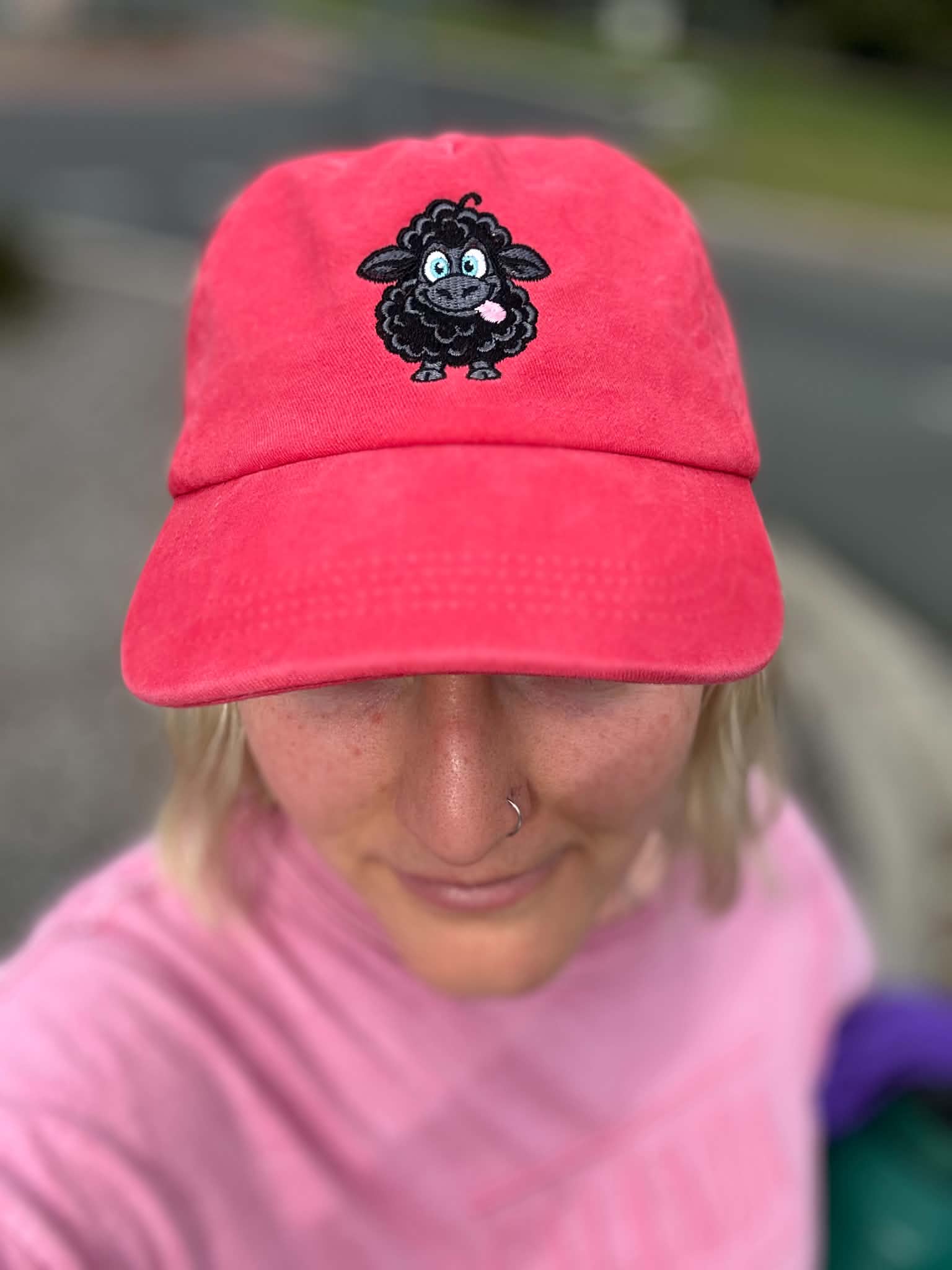 Washed red cotton cap with an embroidered black sheep sticking its tongue out