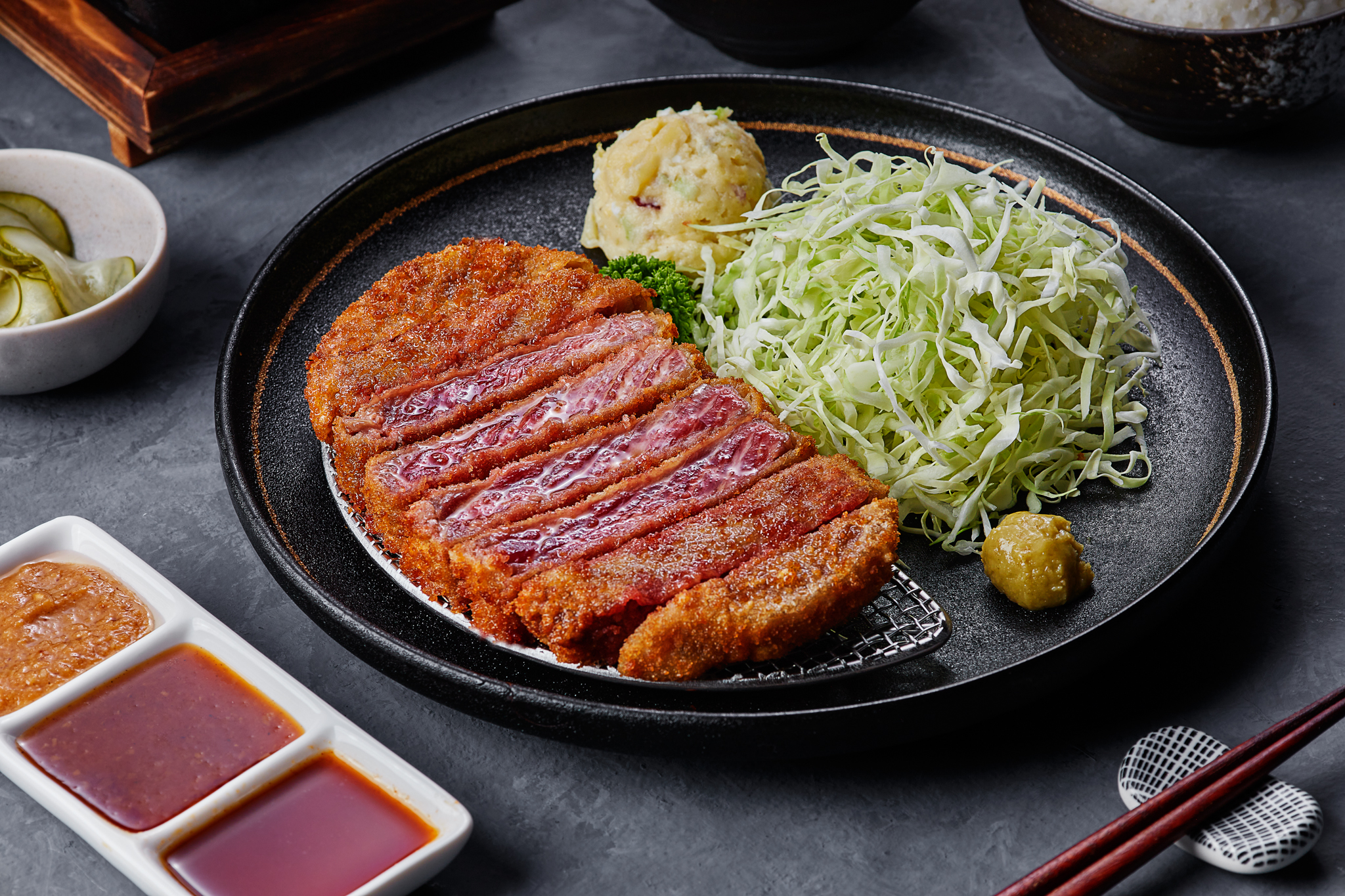 Crispy breaded beef cutlet served with fresh cabbage and dipping sauces.
