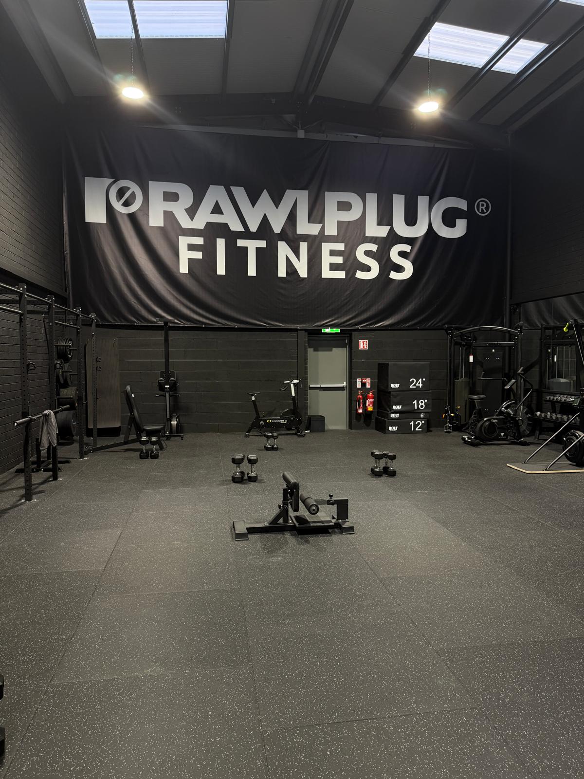 Rawlplug Fitness gym floor in Ashbourne with training equipment and branded banner.