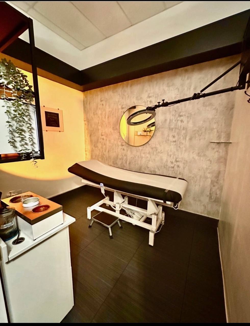 Private treatment suite with warm lighting, ring light, and treatment bed