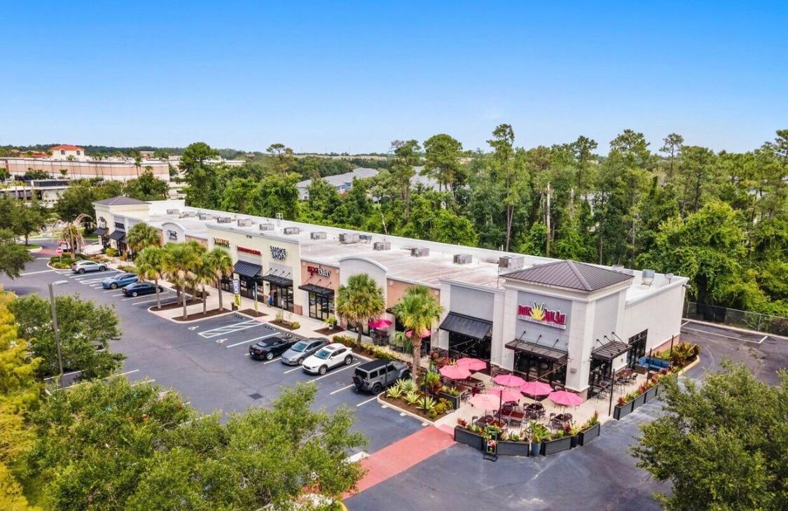 Aerial view of the Waterford Lakes shopping plaza where Your Signature Suites is located, showing the building, parking, and surrounding restaurants