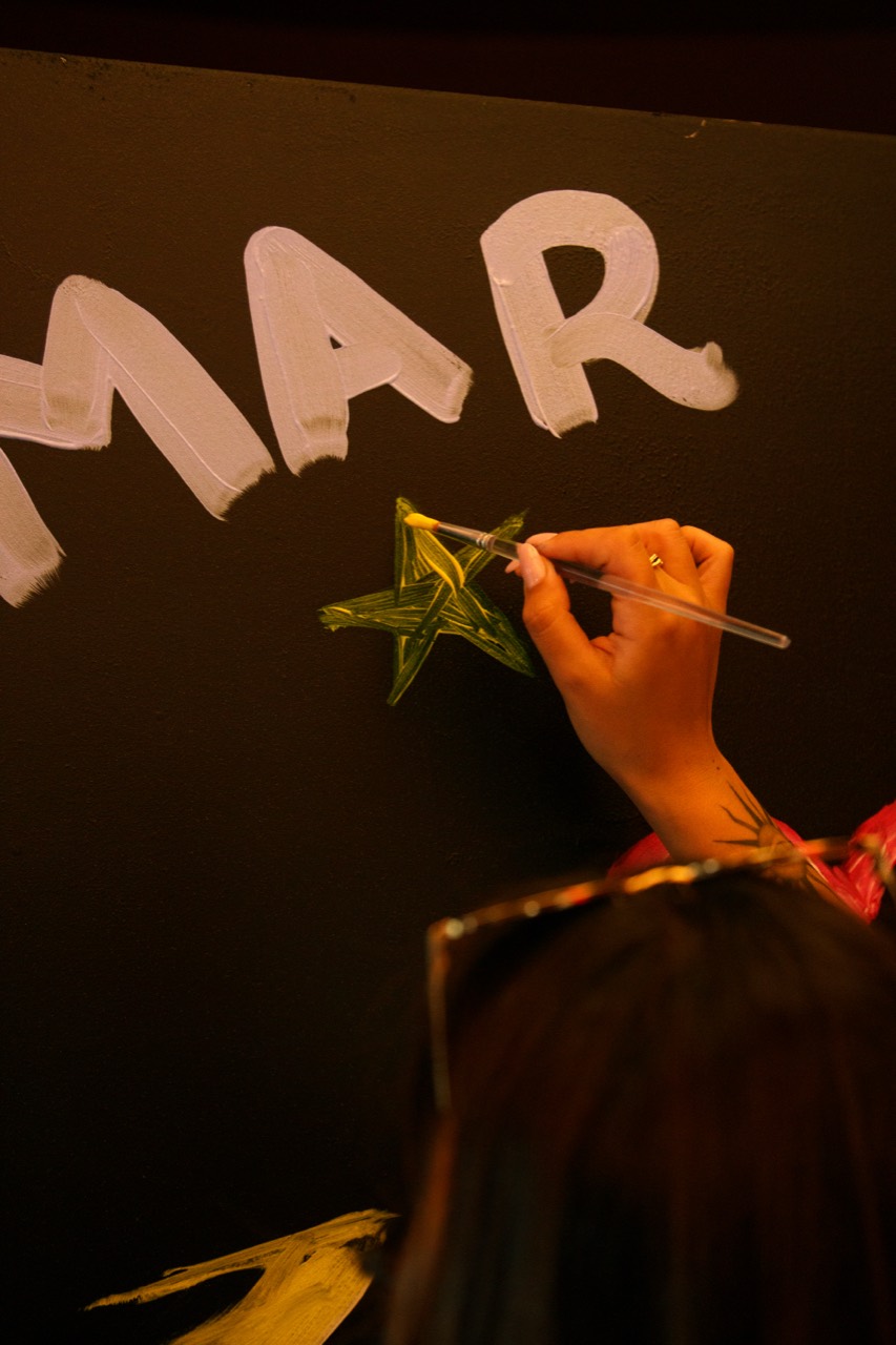 A hand painting a star on the community canvas