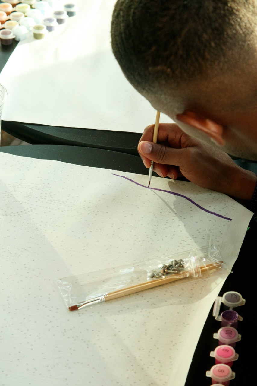 A guest carefully painting a numbered canvas