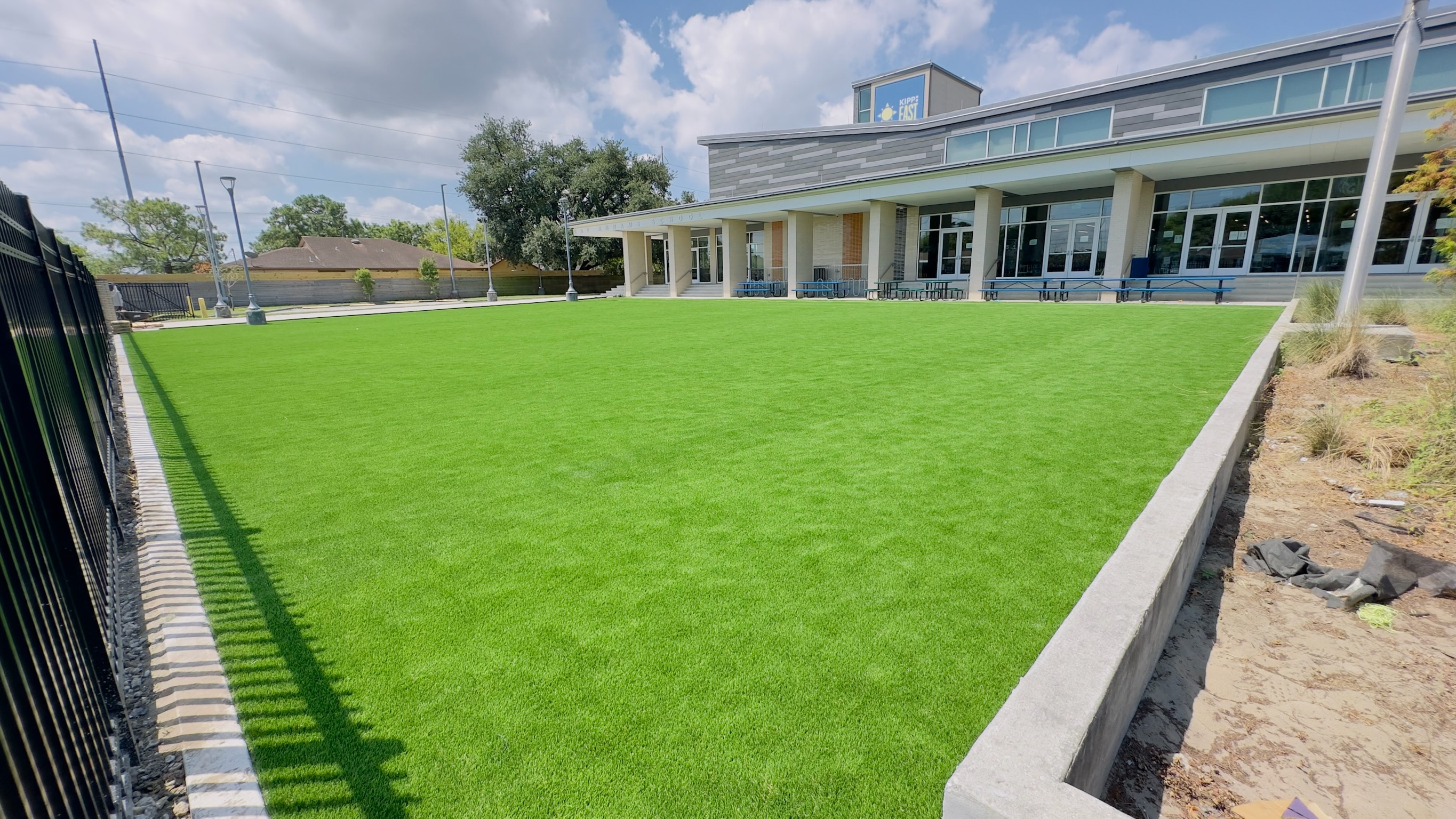 Artificial turf lawn bordered by a fence and a long covered porch