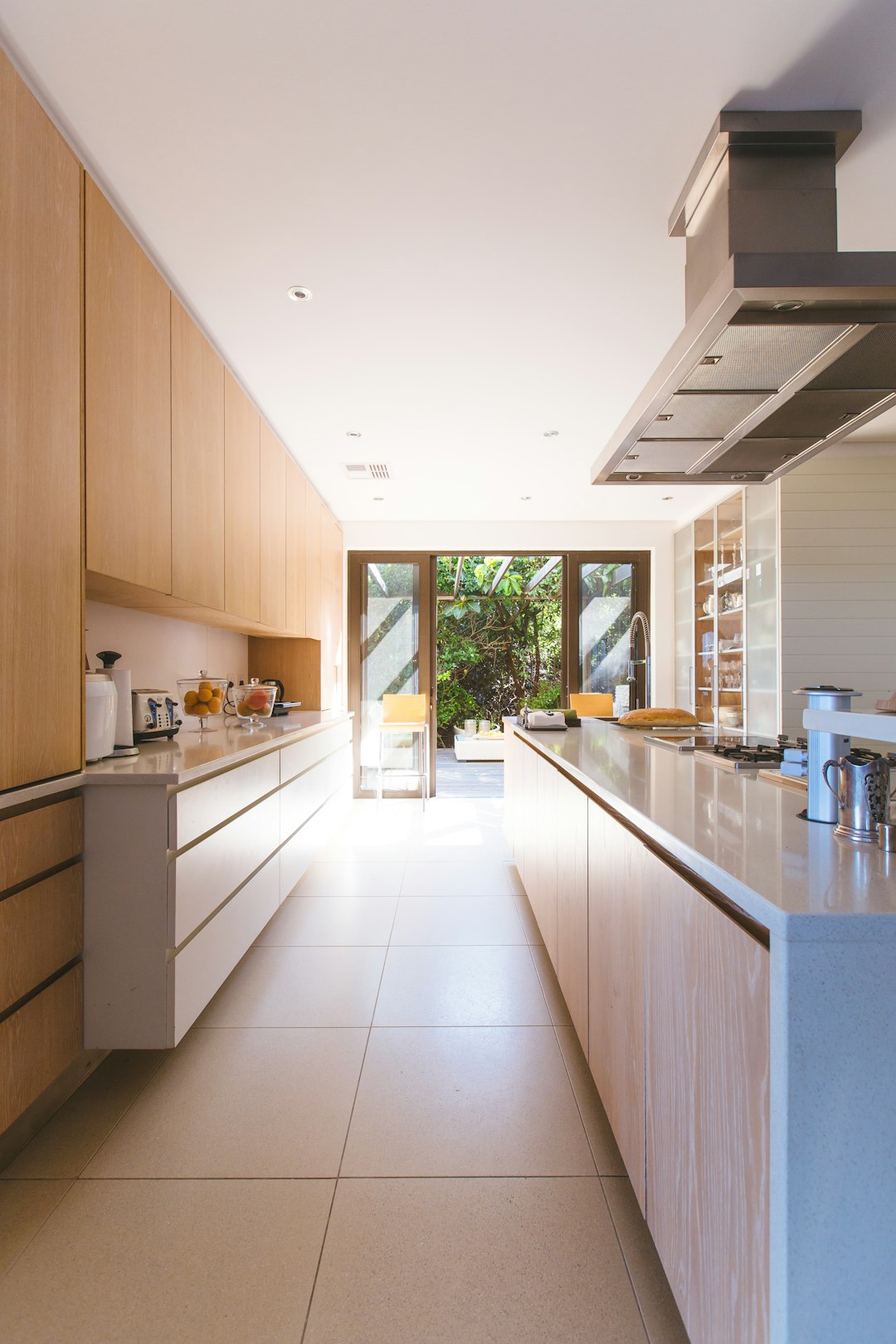 Bright modern staged kitchen with wood cabinets, large island, and natural light from sliding glass doors.