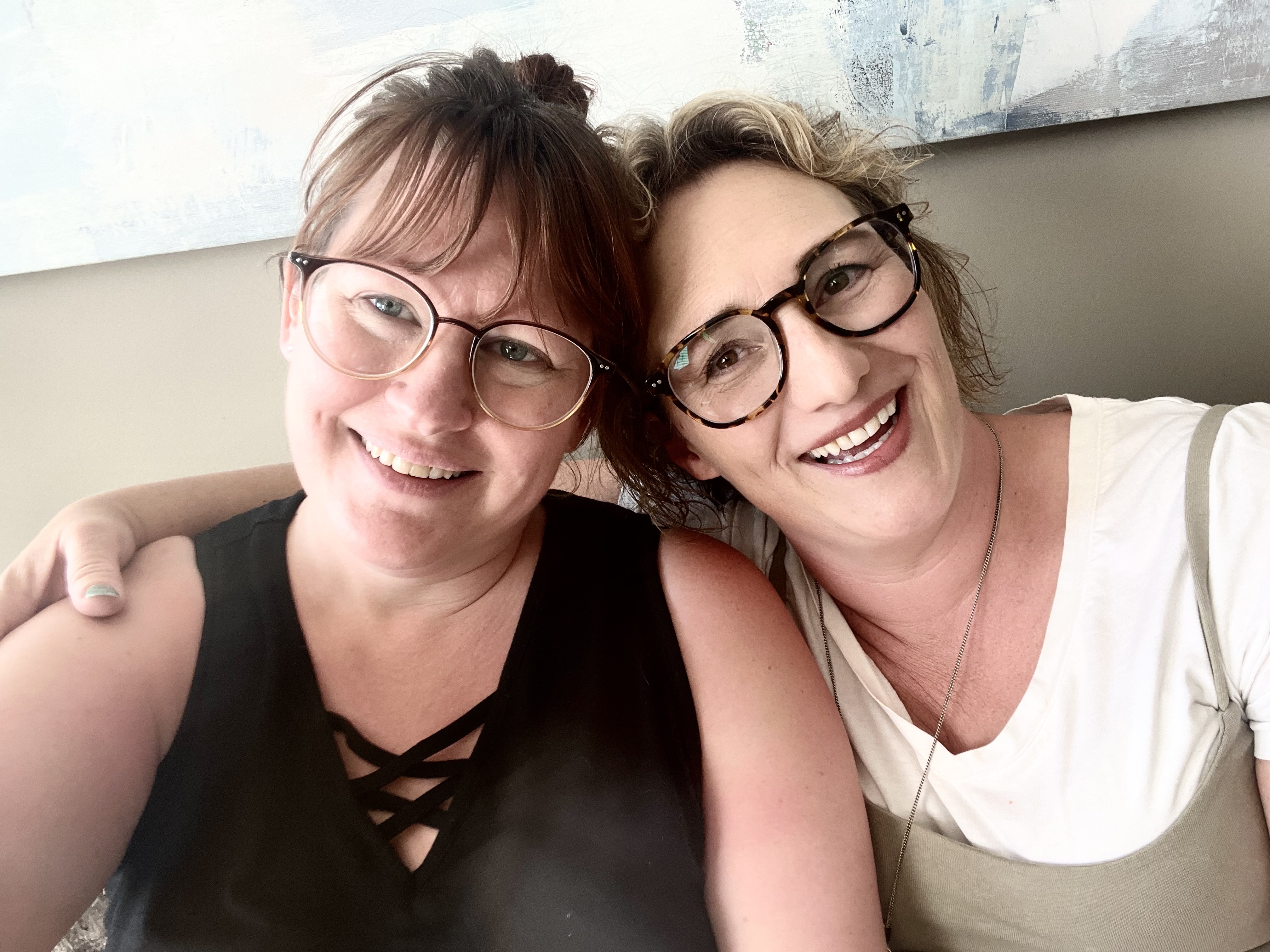 The Staff of Fresh Moves Home Staging. Two women both with glasses smiling at the camera. One woman has her arm thrown around the others shoulders.