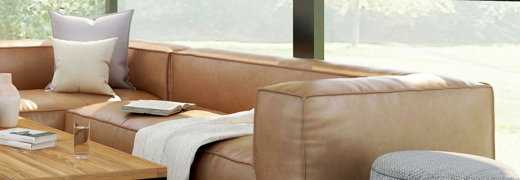 Staged modern living room with tan leather sectional, wood coffee table, and bright natural light from large windows.