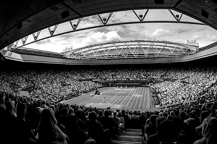 Centre Court at the All England Club during a Wimbledon match, a full crowd in the stands beneath the retractable roof