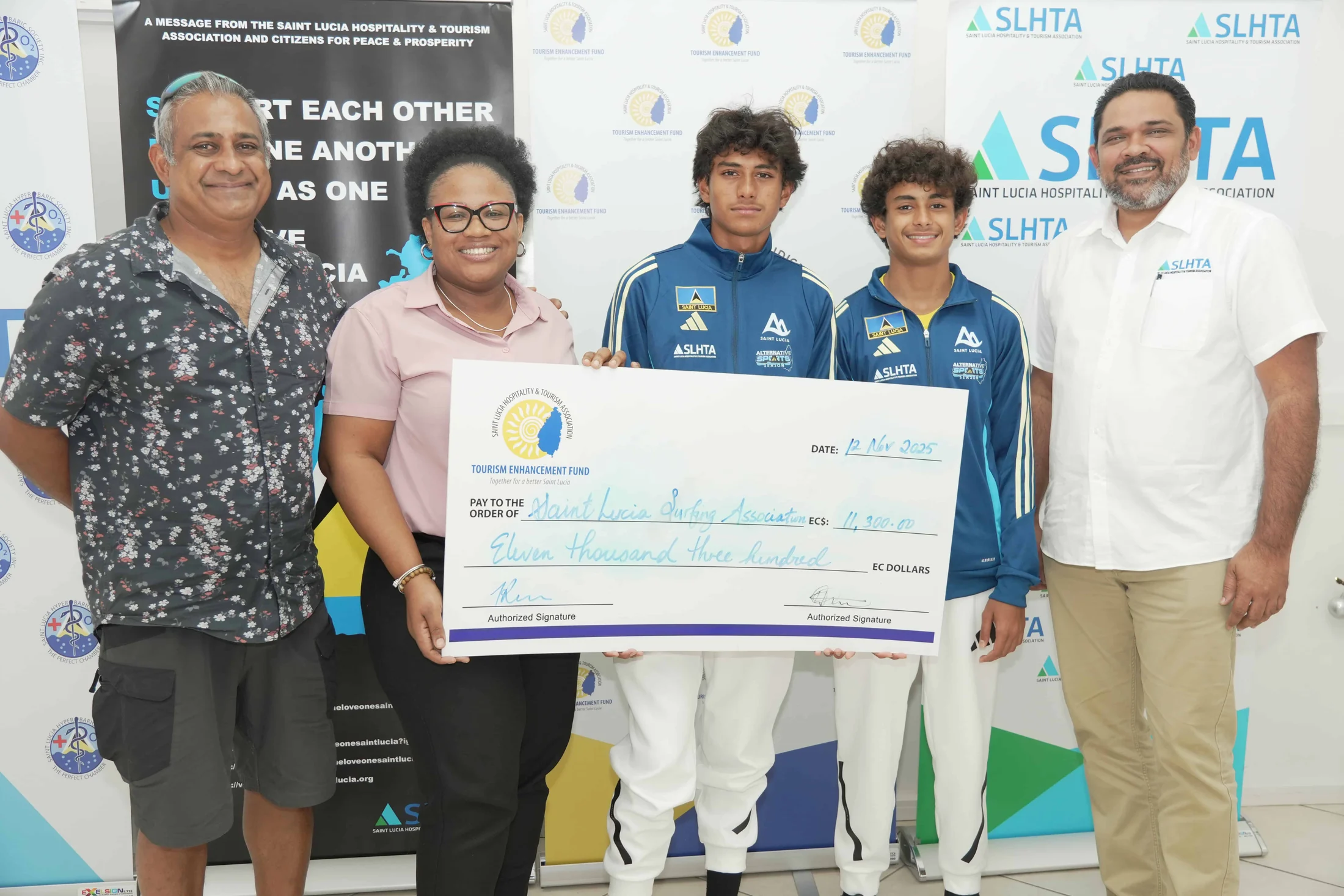 Two young fencers in team jackets receive a TEF cheque with SLHTA representatives