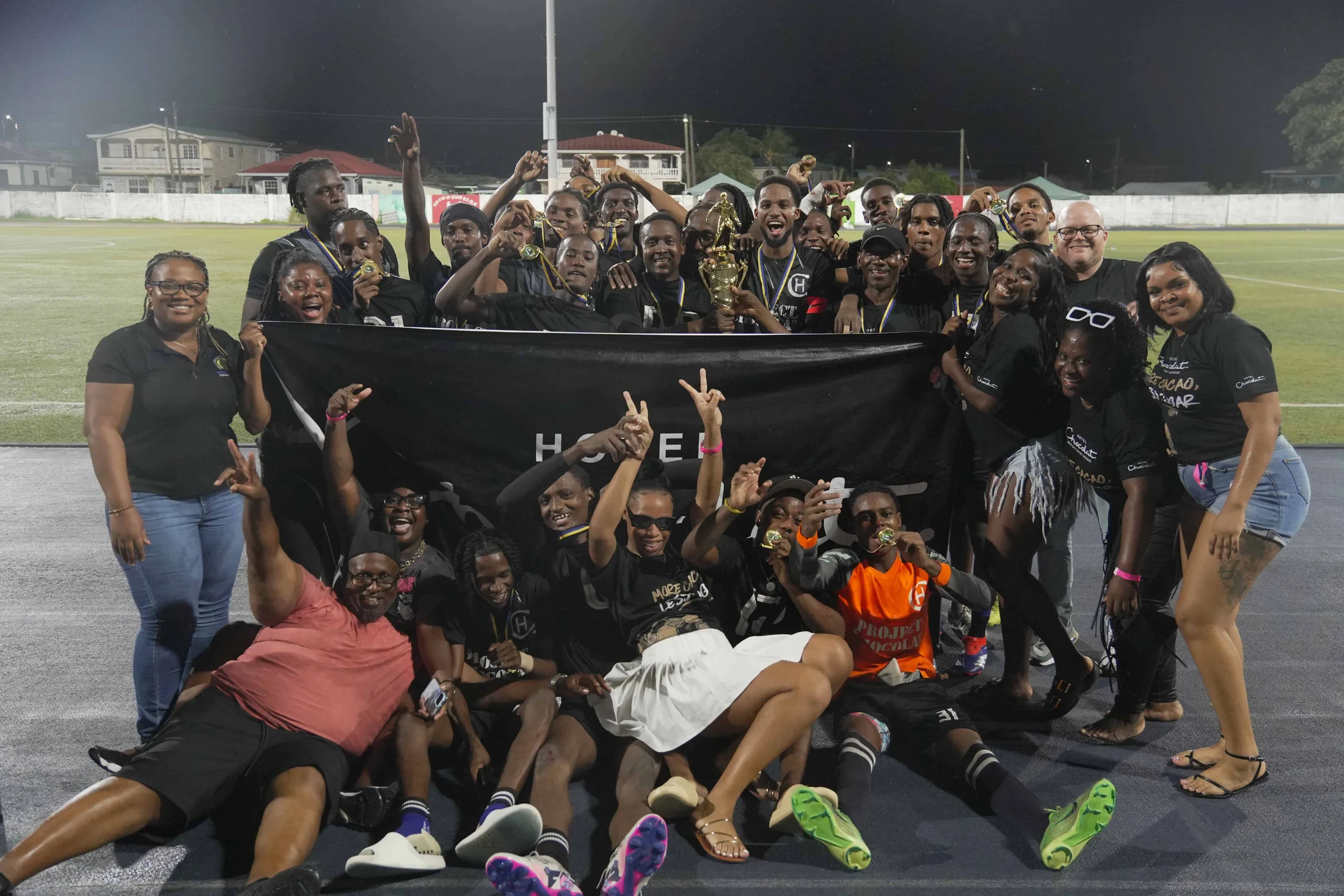 A girls' football team celebrates a win with their trophy at night