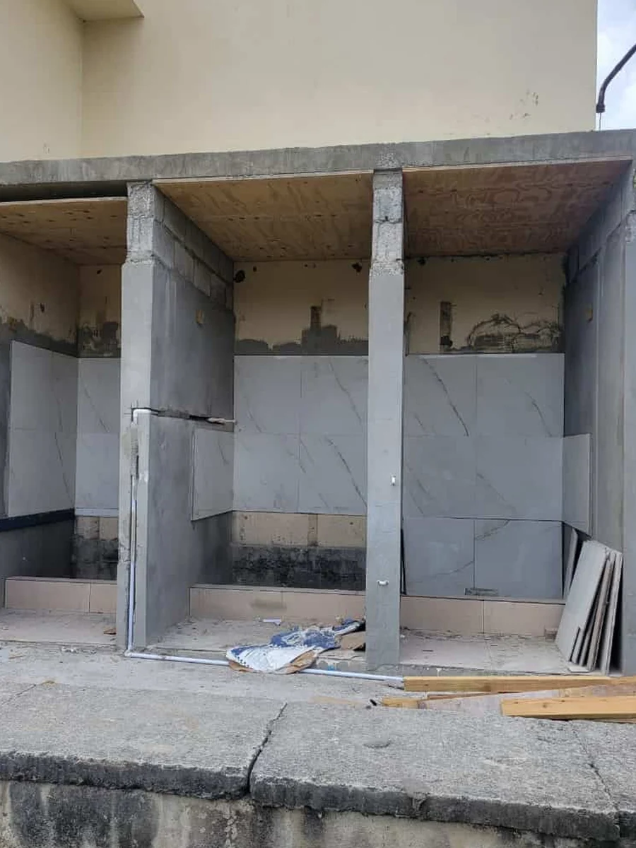 A school washroom block before refurbishment: bare concrete stalls