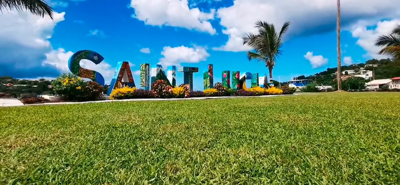 The painted Saint Lucia sign on the lawn above the harbour and green hills