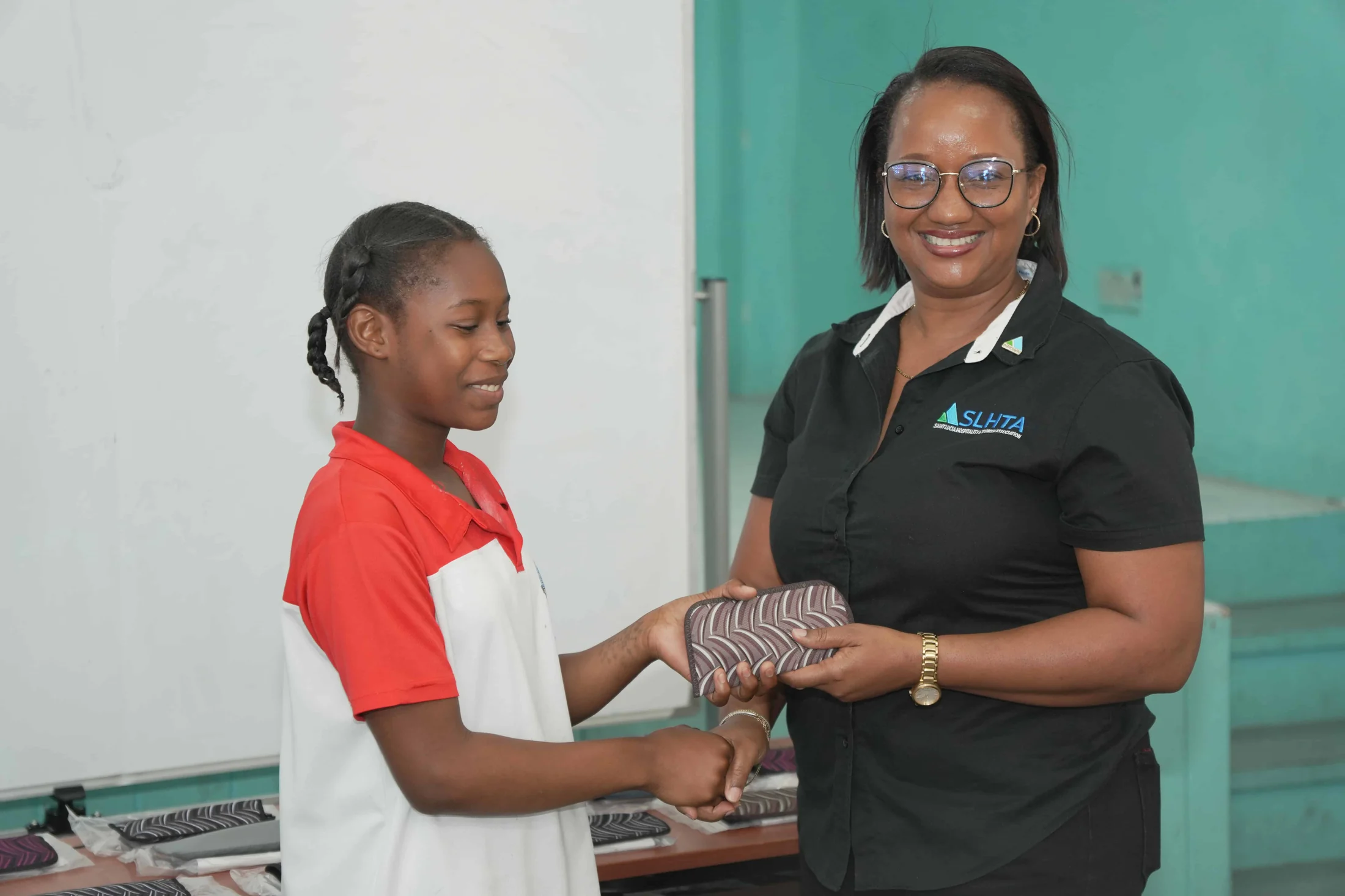 An SLHTA staff member hands a gift to a schoolgirl