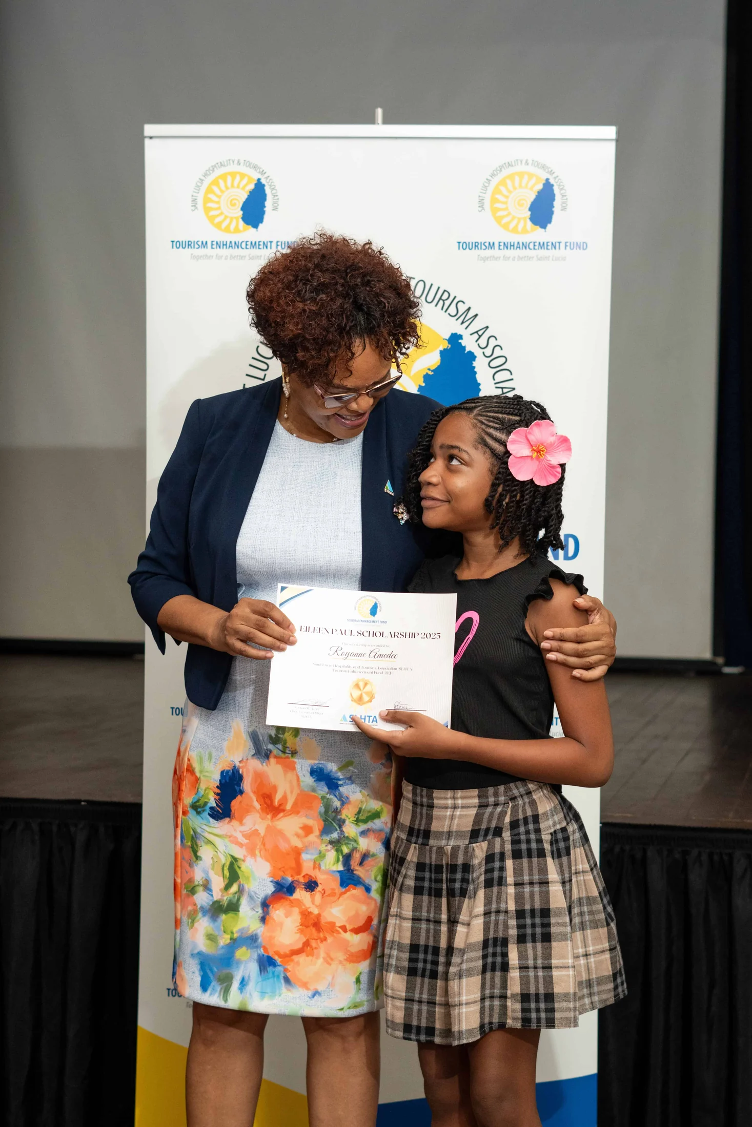 An Eileen Paul Scholarship recipient hugs a presenter while holding her certificate