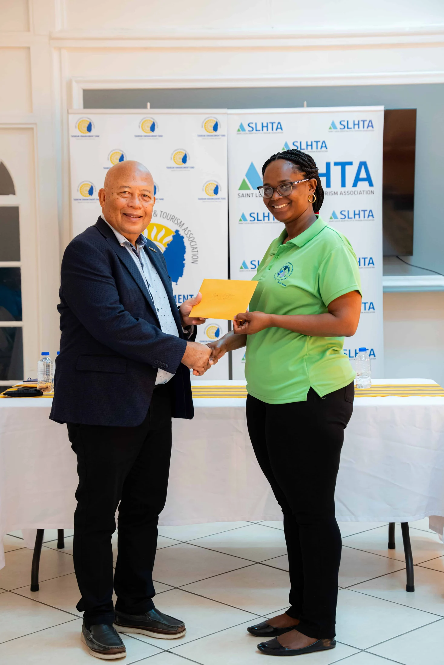 An SLHTA representative hands a grant envelope to a recipient