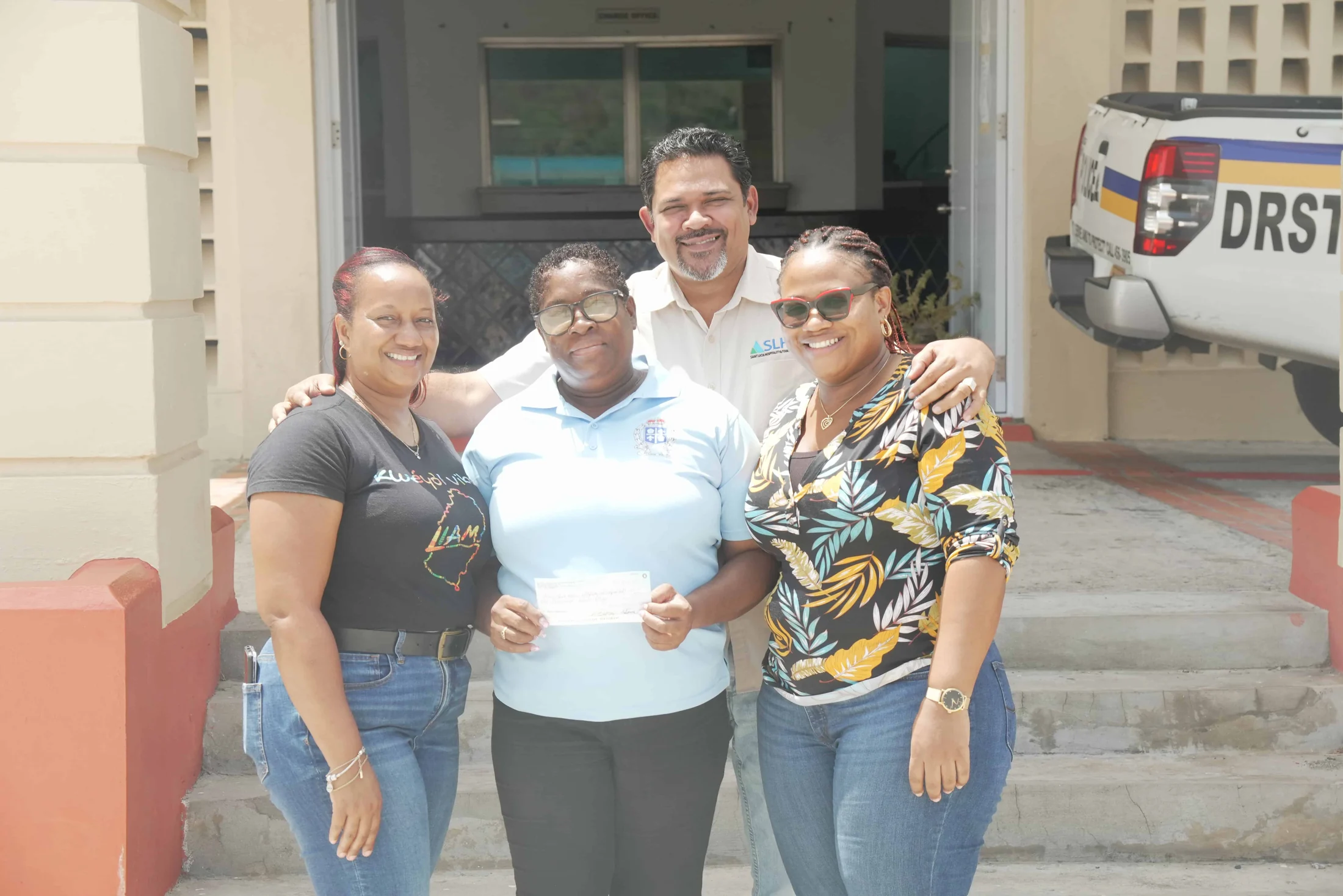 A TEF cheque handover on the steps outside a community building