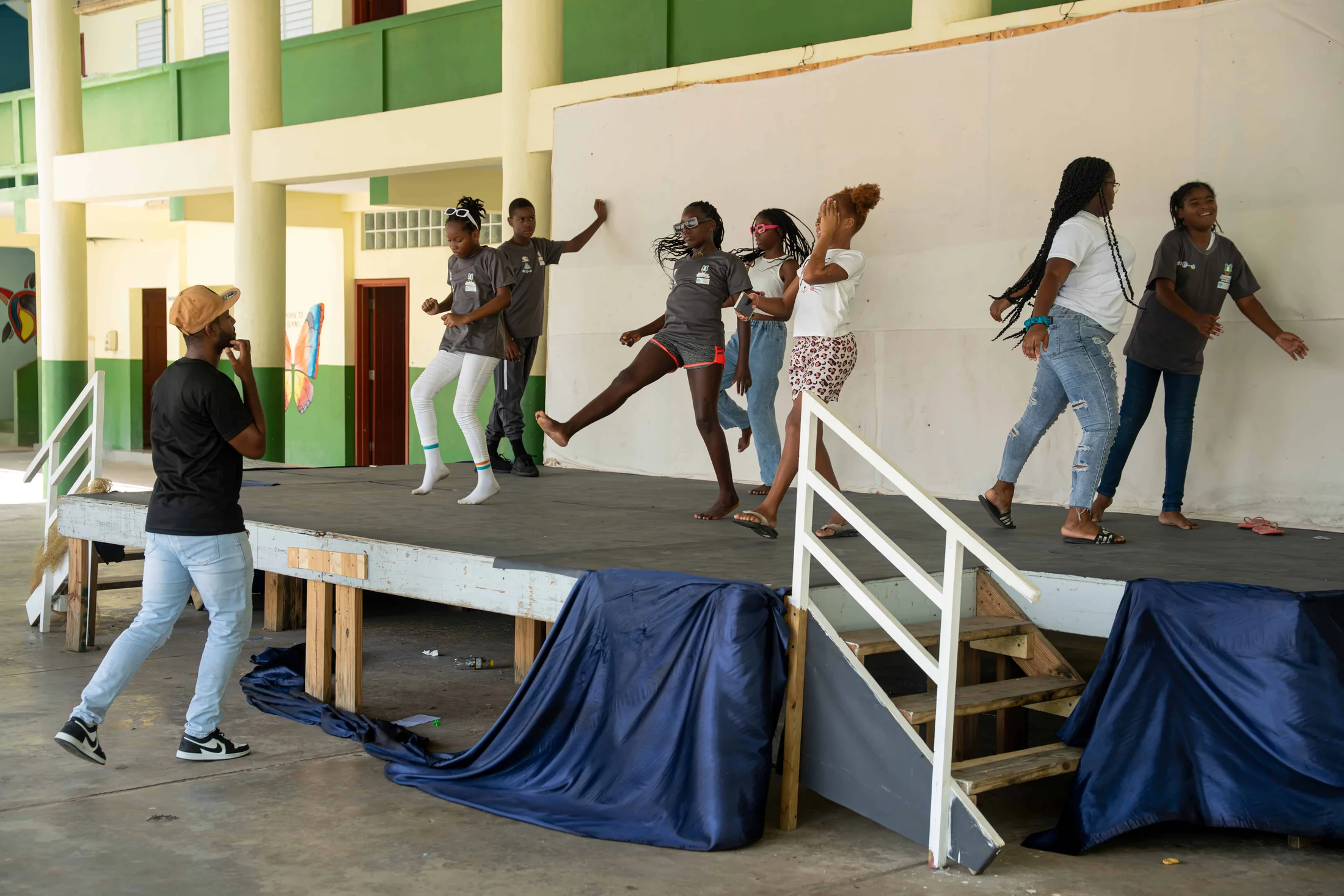 Young people rehearse a dance routine on an outdoor school stage
