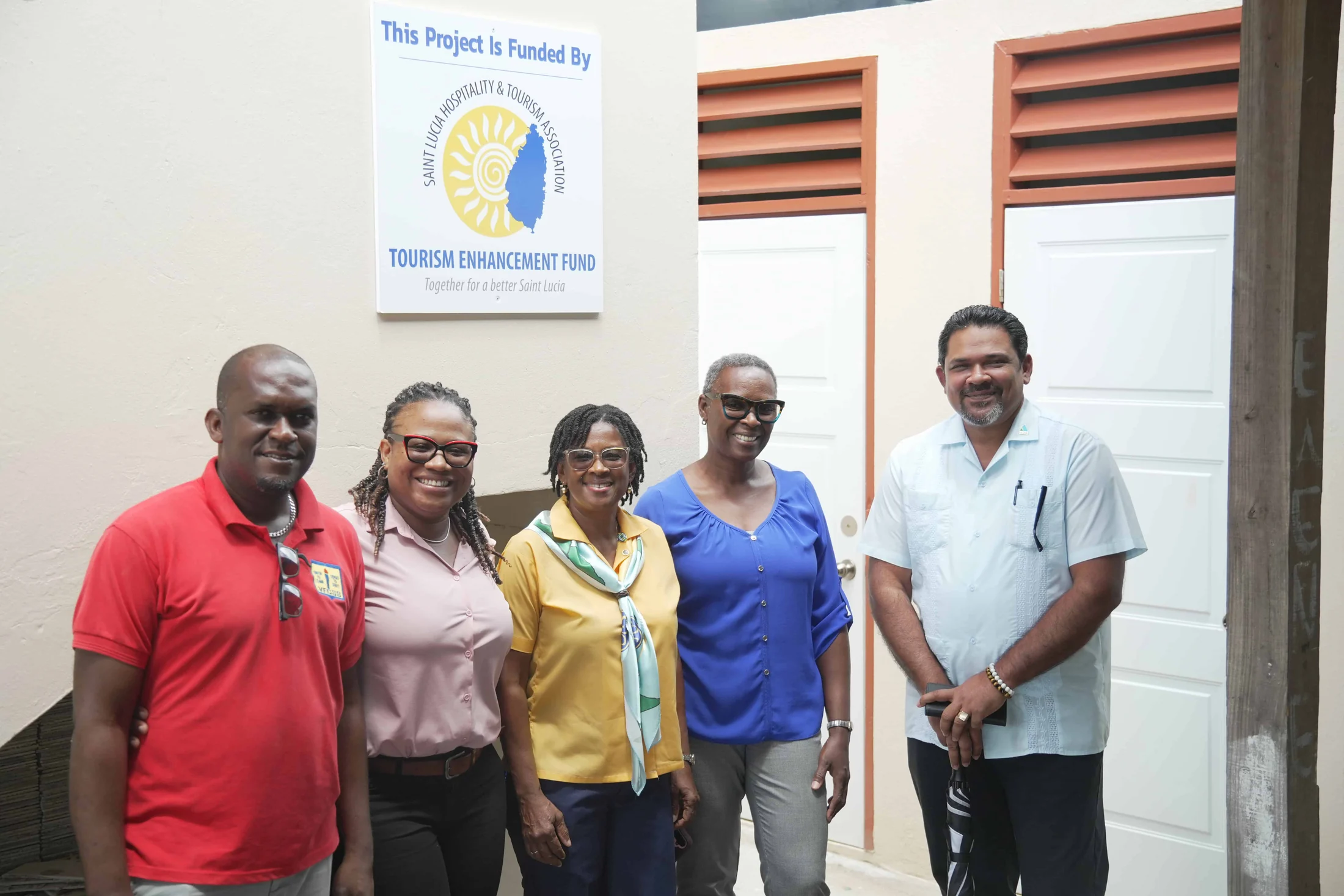 School staff beside a plaque reading 'This project is funded by the Tourism Enhancement Fund'