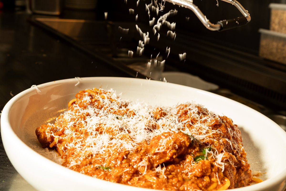 Parmesan grated over a bowl of Spaghetti Bolognese