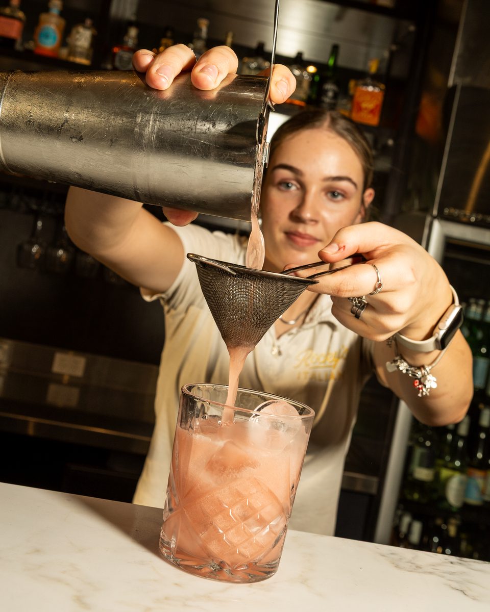 Bartender straining a Chambord Vanilla Sour at the Rocky's Italian bar
