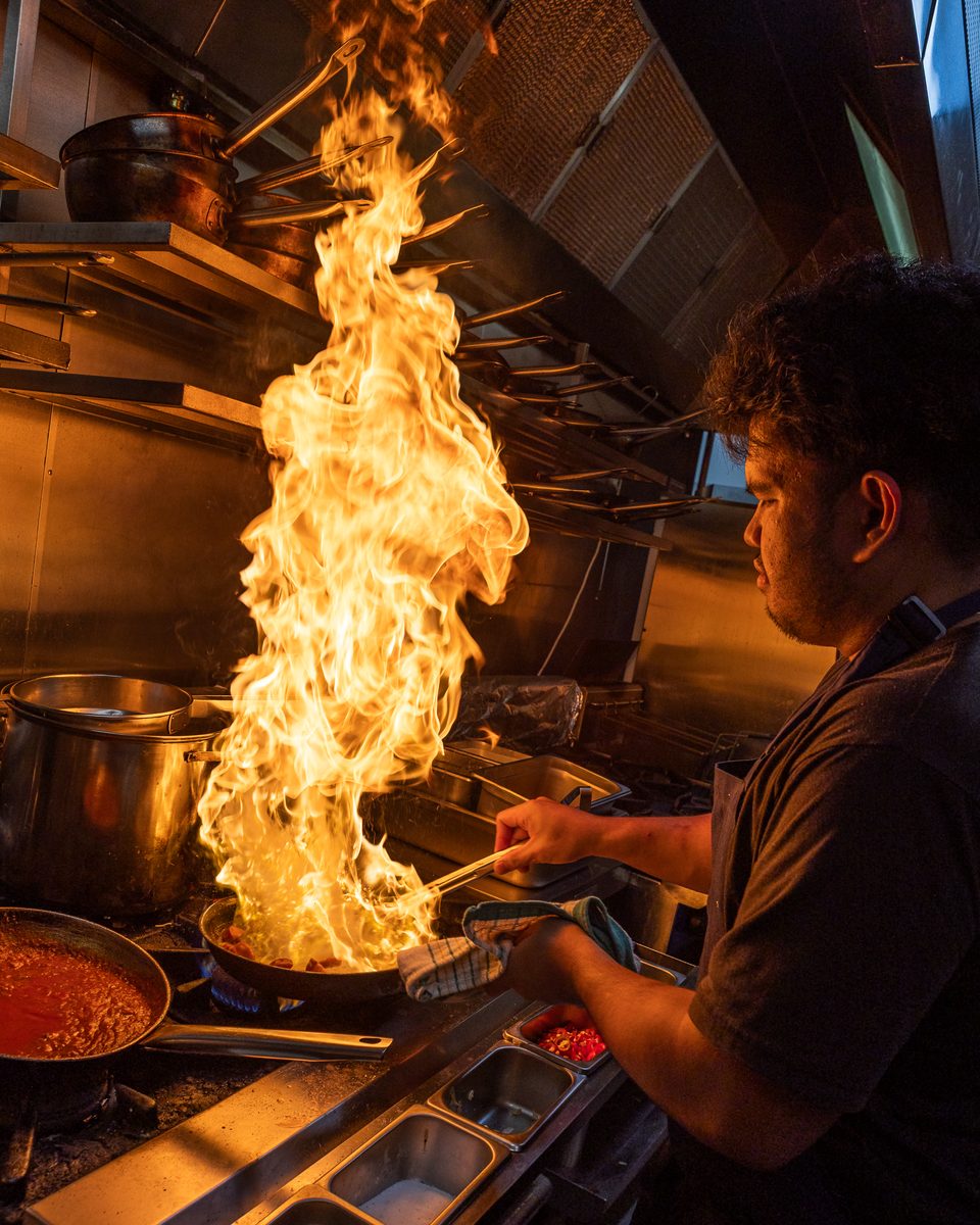 Flames rising from a pan on the Rocky's Italian kitchen line