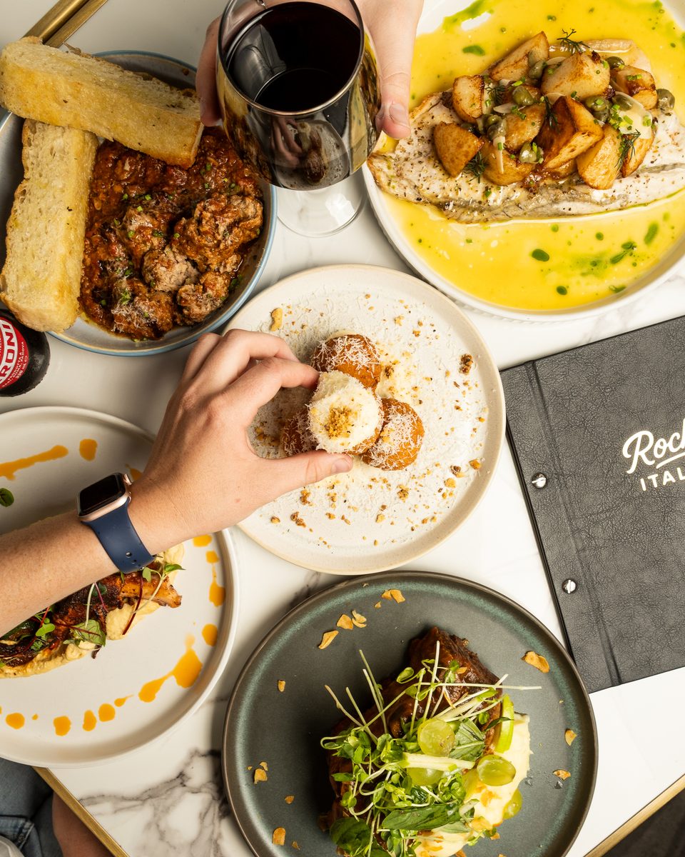 Overhead of hands sharing plates across a full table