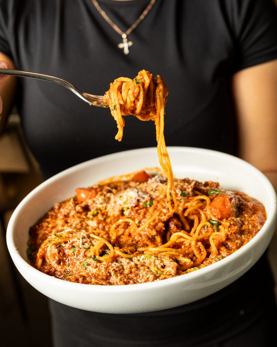 Spaghetti Bolognese twirled on a fork above the bowl