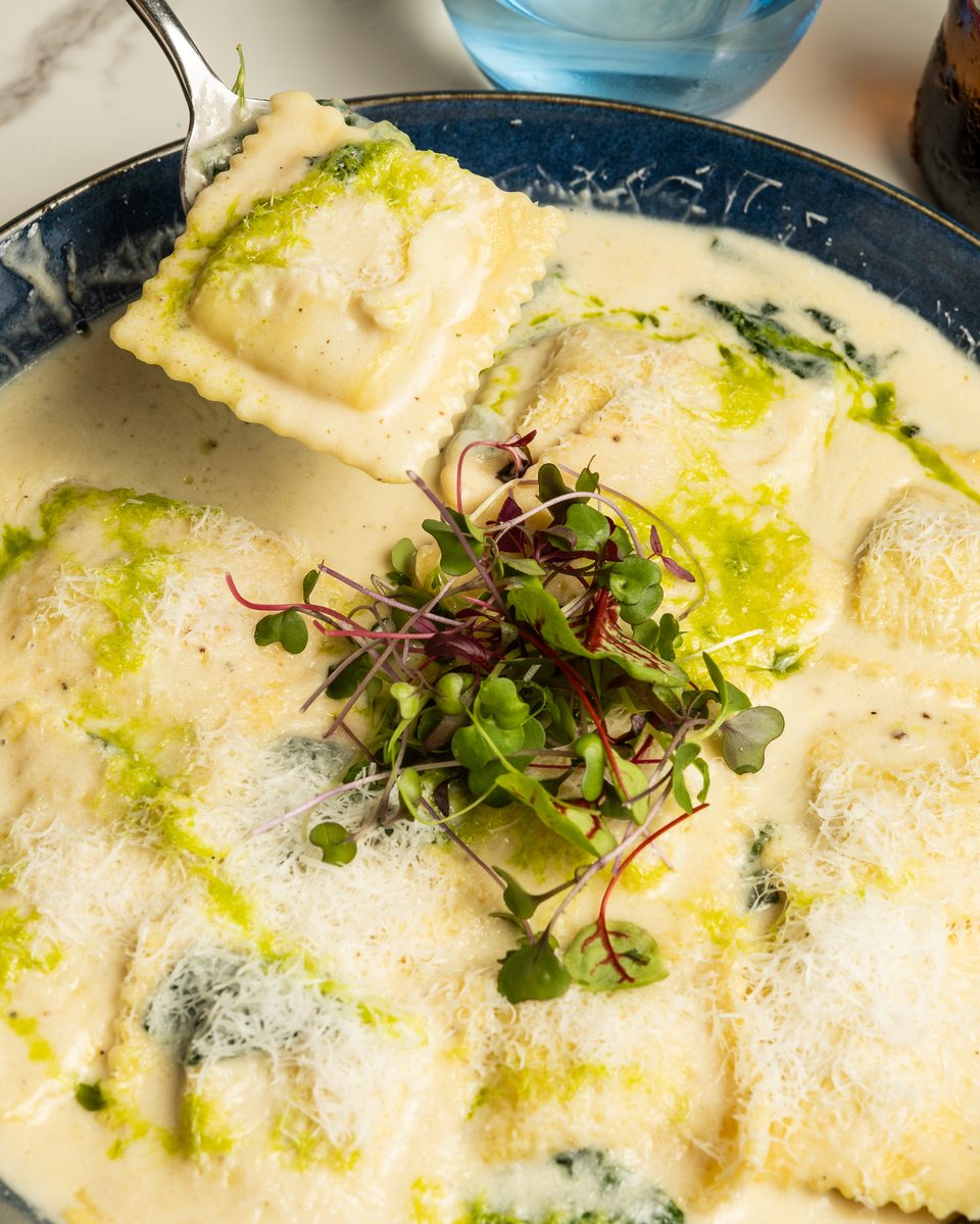 Spinach and ricotta ravioli in a creamy garlic sauce with micro herbs