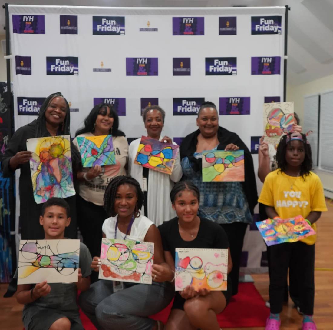 Families and kids smiling and holding up colorful artwork they made at an IYH Fun Friday art night