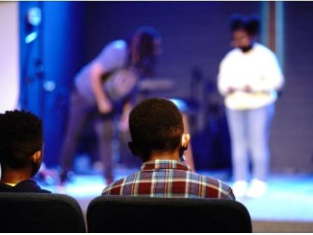 Young audience members watching performers on stage