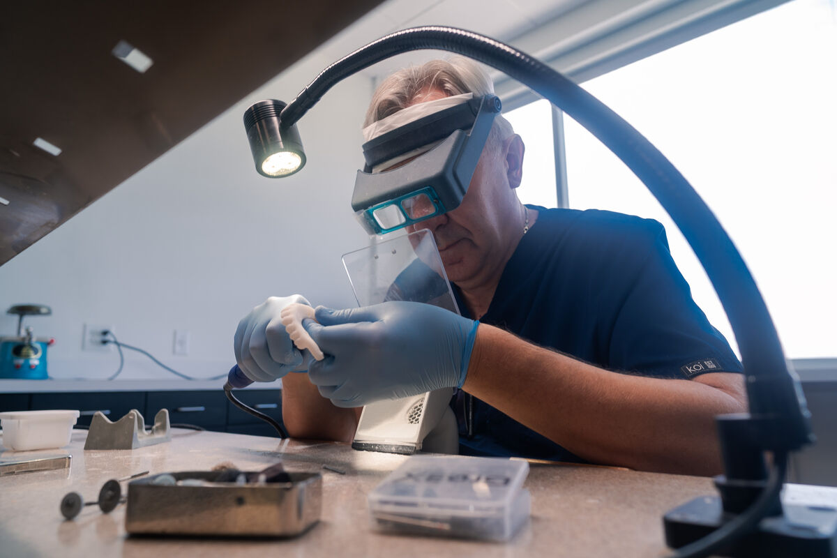 An Elite Dentistry lab technician finishing a restoration under magnification