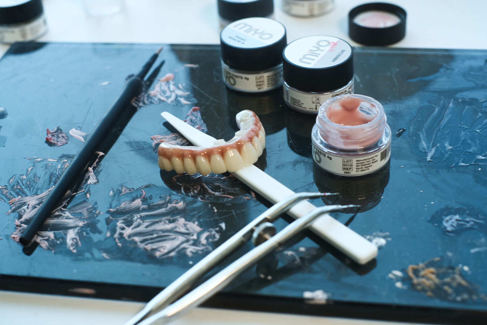 A zirconia arch on the lab bench beside stains and finishing tools