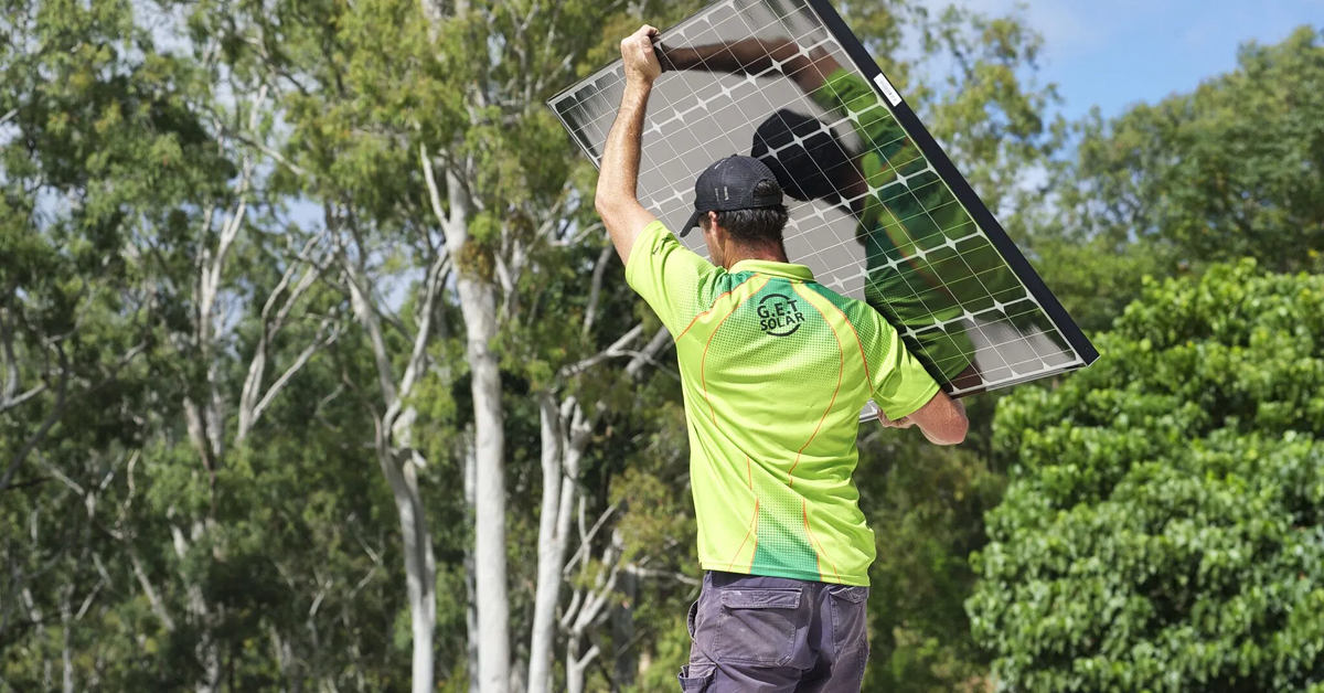 A GET installer carrying a solar panel