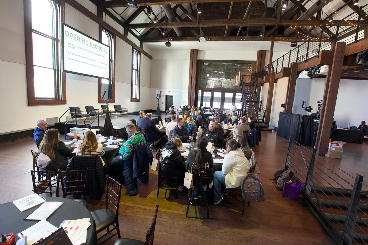 A full room of attendees seated at round tables during a session