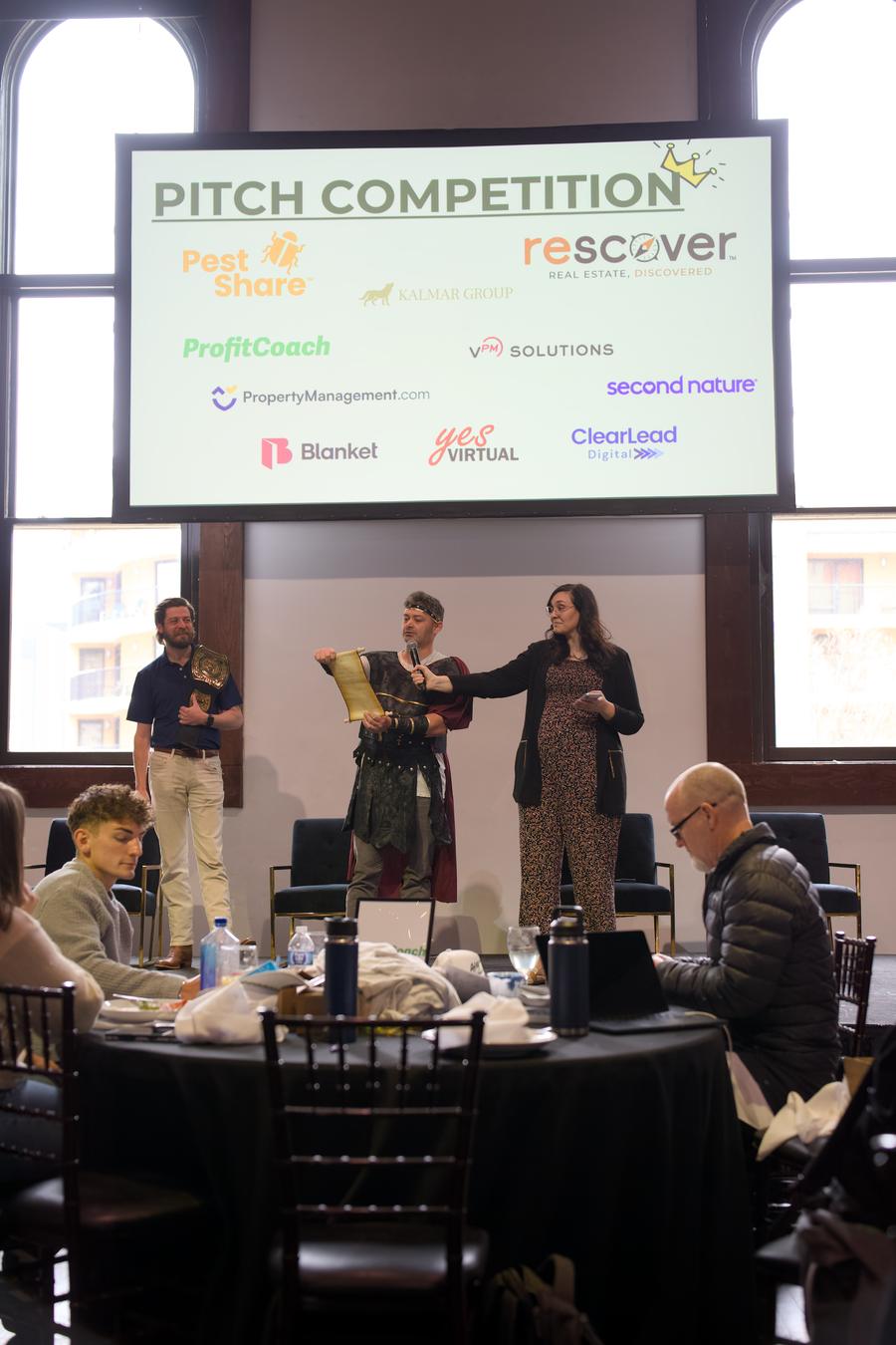 The pitch competition on stage with sponsor logos displayed behind
