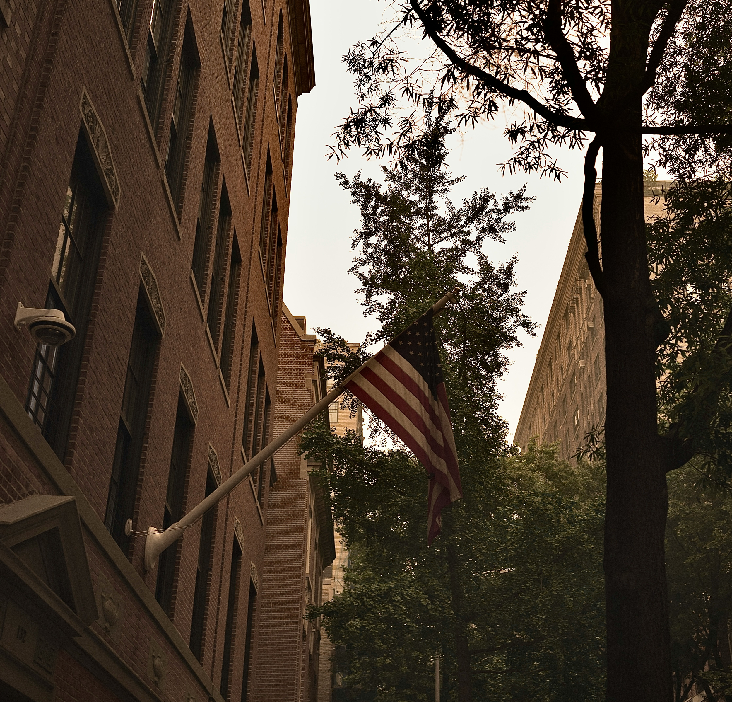 Modern white kitchen with natural light, wood stools, and large windows overlooking Manhattan