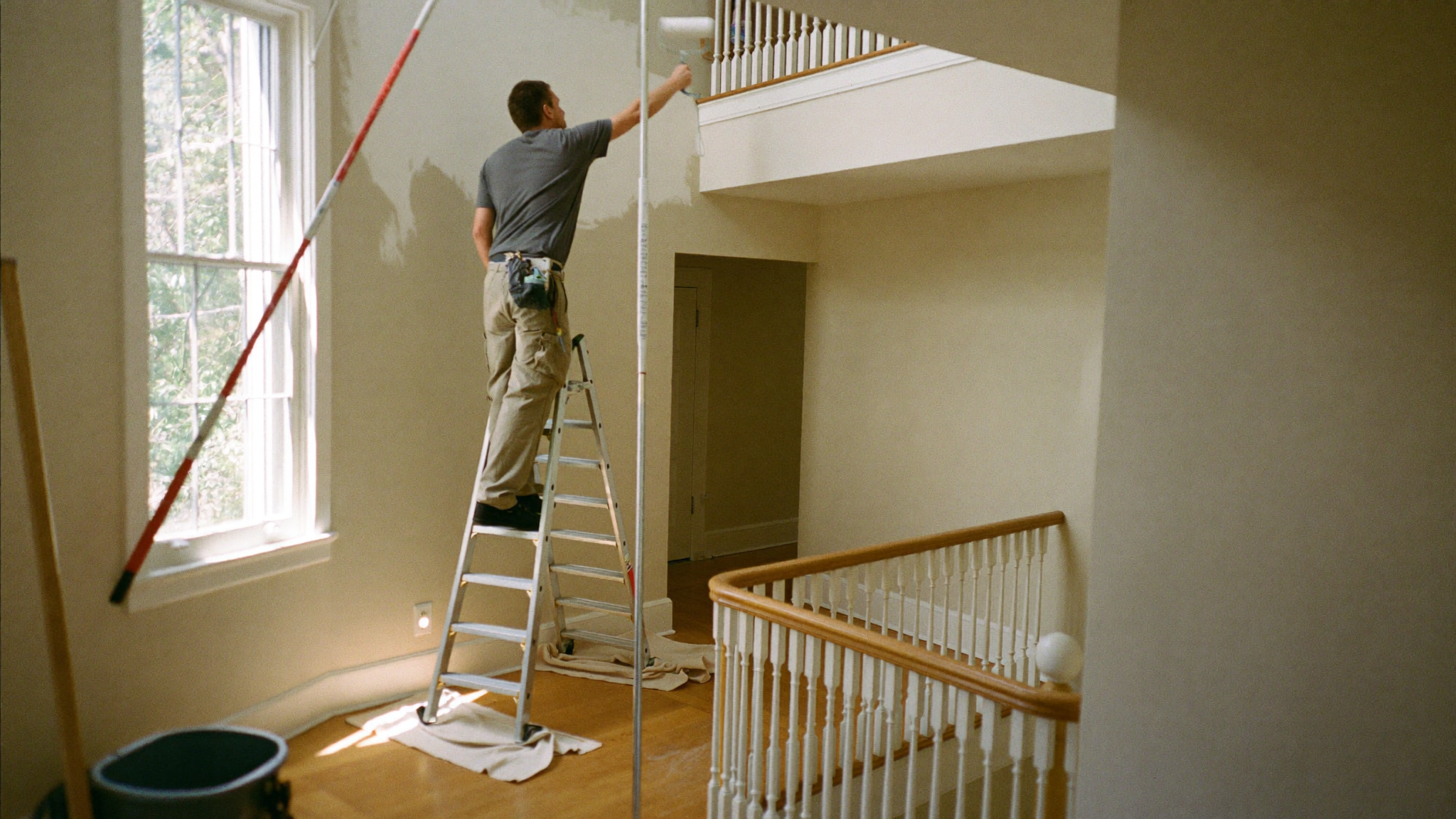 Close-up of a painter brushing a crisp line of white enamel along window casing and mullions