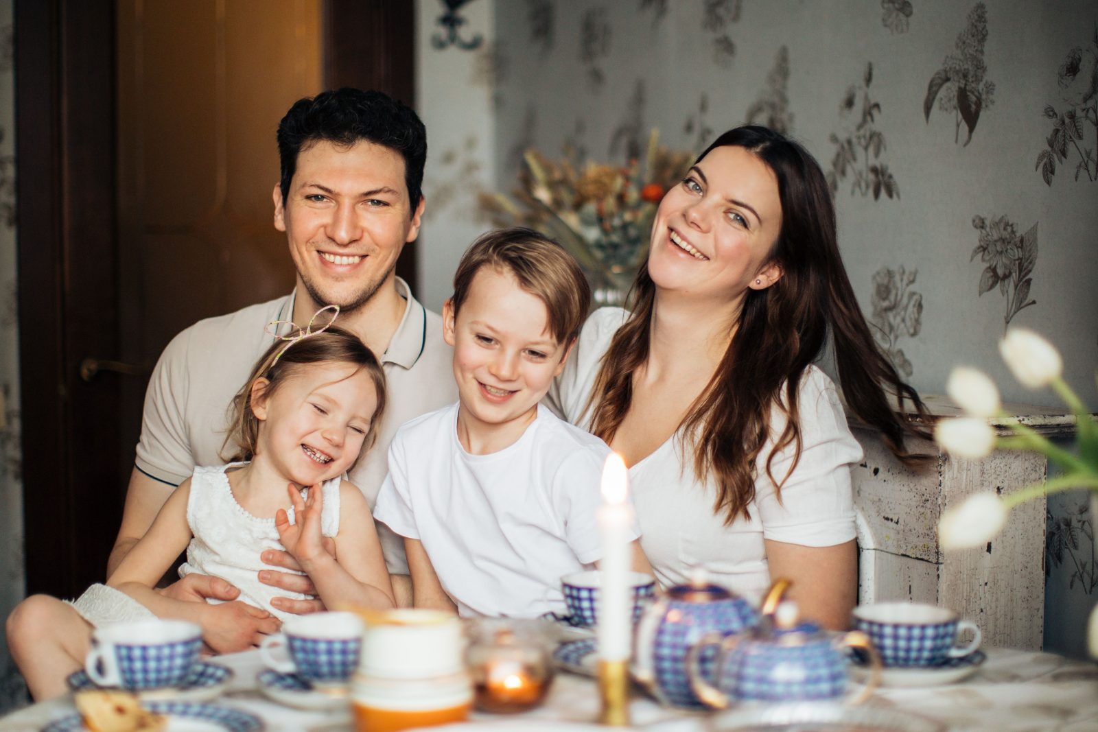 Parents and children laughing together around a table at home