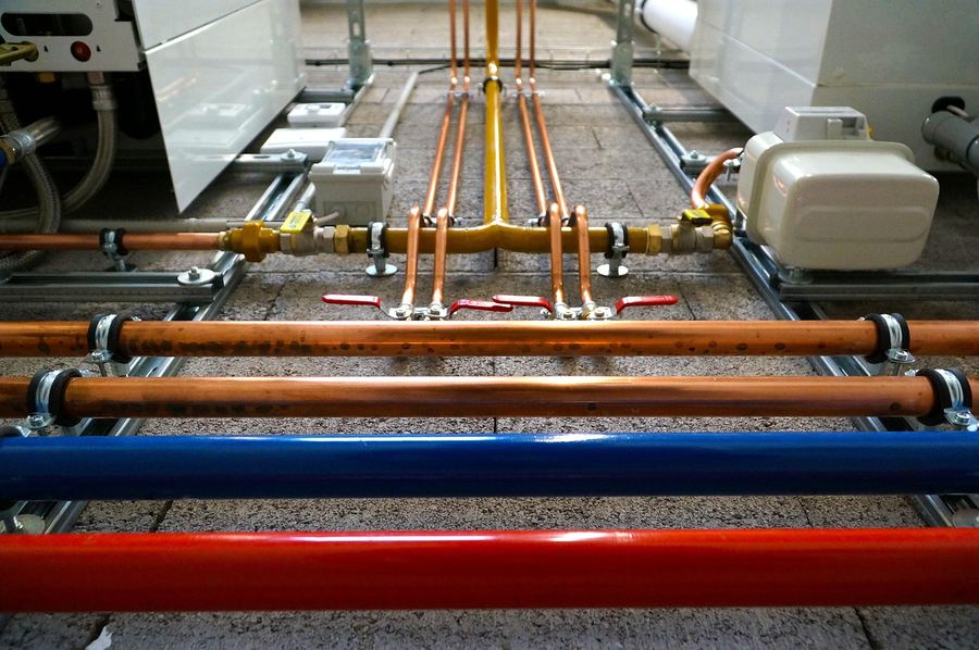 Commercial copper pipe installation with colour-coded distribution manifold and ball valves — commercial plumbing services Uganda, plumber website design by WebFast24 Kampala