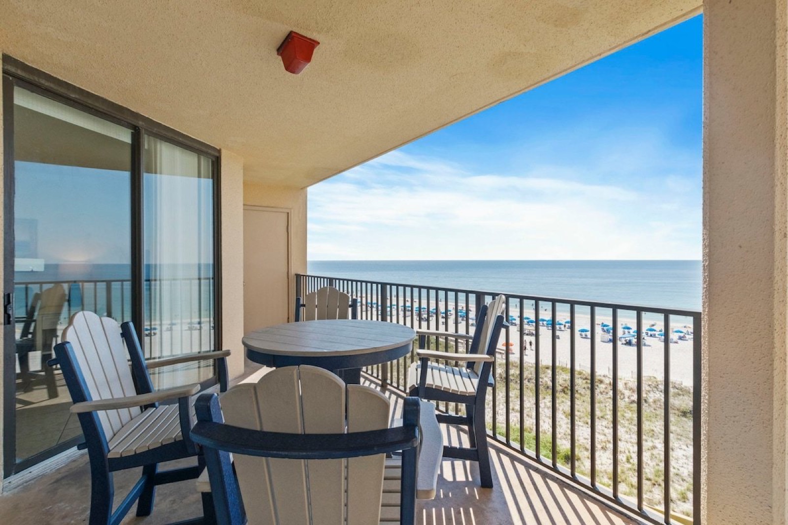 Covered balcony at Phoenix V Unit 501 with a table and chairs, looking over the dune and the Gulf