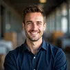 Young male warehouse manager in smart casual workwear, holding a clipboard in a brightly lit warehouse – Trey Lewis testimonial