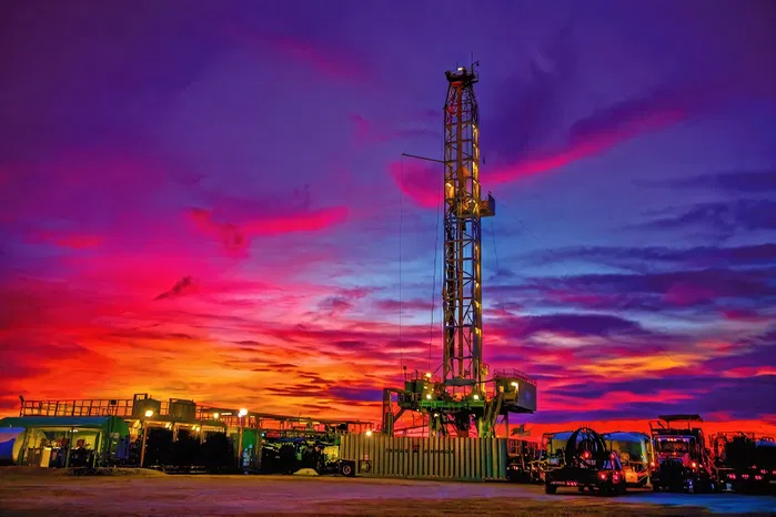 West Texas land rig at blue hour, bright LED lighting on mast and rooms, IR Series family.