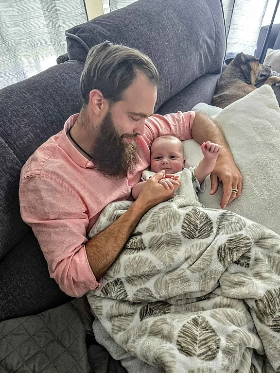 Mike Poarch at home holding his newborn