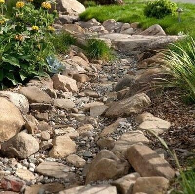 Natural stone pathway providing erosion control in a landscaped garden