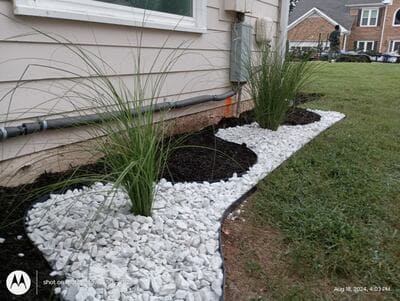 White decorative rock landscaping with ornamental plants near a house exterior