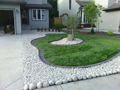 Custom front yard landscaping with grass and white stone accents