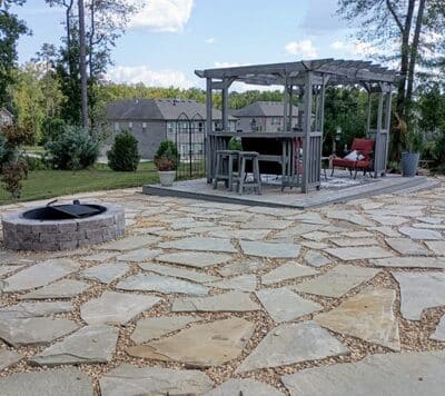 Spacious backyard flagstone patio with a custom fire pit