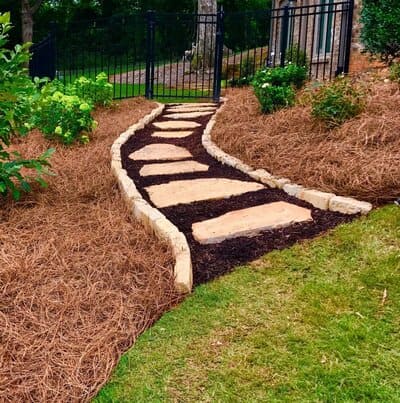 Natural stone garden pathway bordered with pine straw